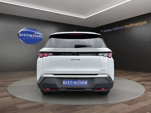 Vue arrière d'un Peugeot 5008 blanc hybride 2025 avec feux LED distinctifs et logo central sur fond showroom.