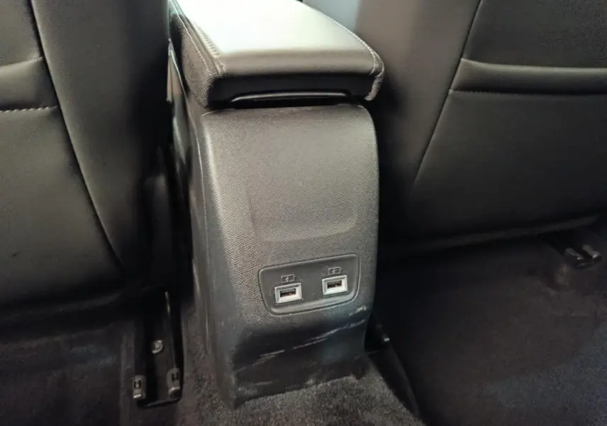 Vue rapprochée de la console centrale arrière noire avec deux ports USB dans l’habitacle d’une Peugeot 208 Electrique gris clair.