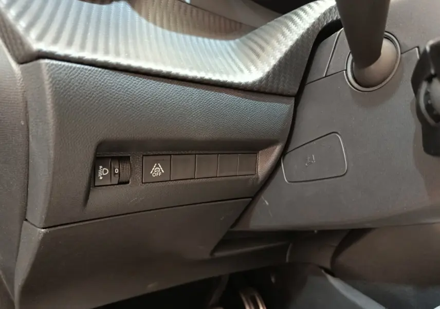 Détail intérieur côté gauche du tableau de bord gris foncé avec commandes d’éclairage et aide à la conduite Peugeot 208 Electrique.