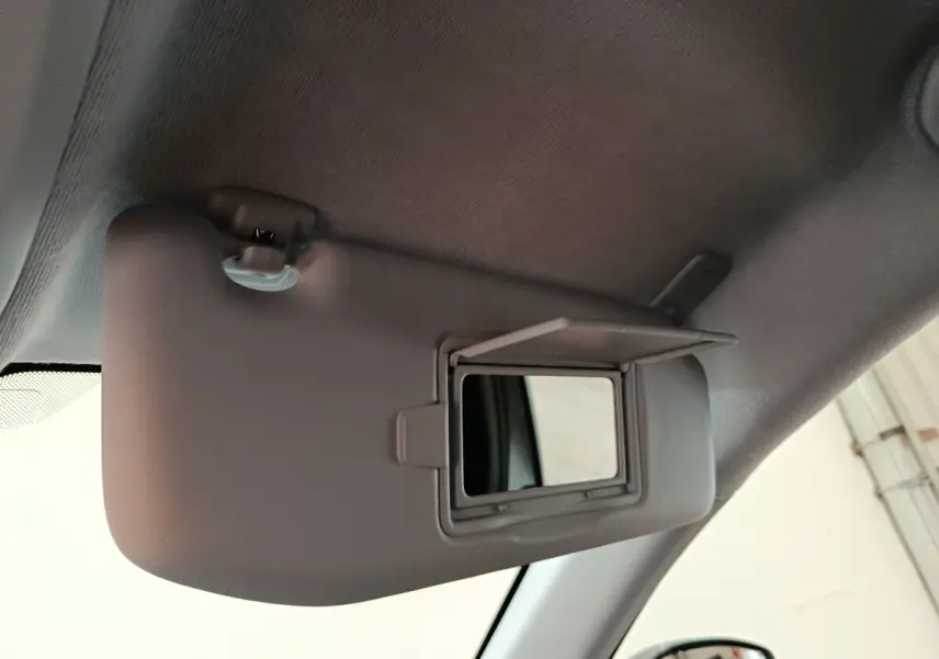 Miroir de courtoisie ouvert sur pare-soleil côté conducteur dans l'habitacle d'une Peugeot 208 électrique gris clair.