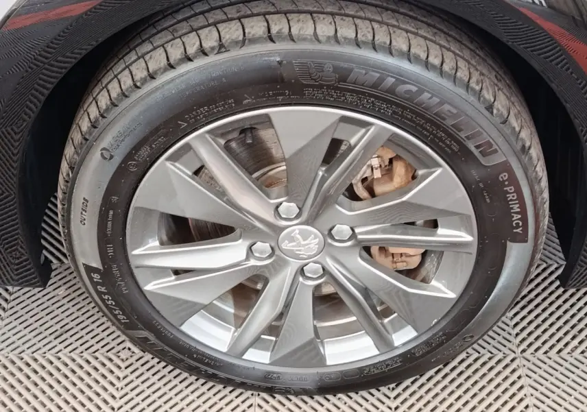 Gros plan sur la roue avant droite grise d'une Peugeot 208 électrique avec jante alliage et pneu Michelin.