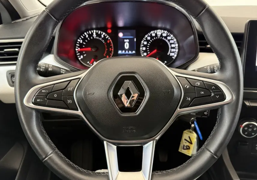 Vue rapprochée du volant cuir noir de la Renault Clio 2023 avec commandes intégrées et tableau de bord éclairé.