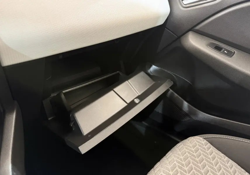 Gros plan sur la boîte à gants ouverte côté passager de la Renault Clio Evolution TCe 100 GPL 2023, intérieur noir et blanc.