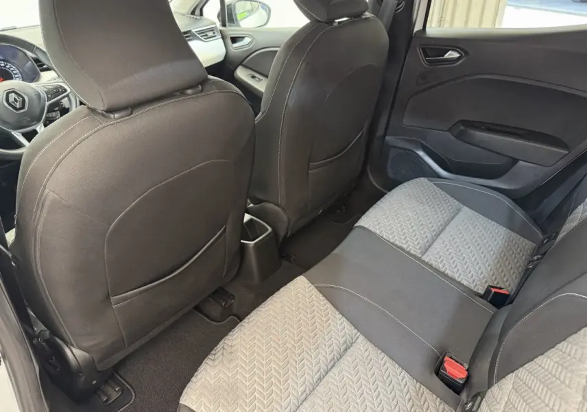 Vue intérieure arrière droite de la Renault Clio 2023 avec sièges tissu gris et noir et tableau de bord partiellement visible.