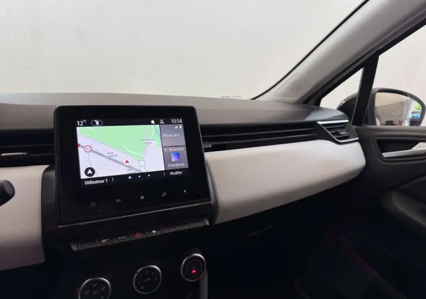 Tableau de bord côté passager de Renault Clio blanc 2023 avec écran tactile central affichant la navigation.