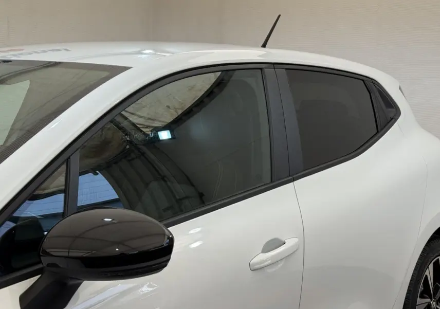 Vue latérale gauche d'une Renault Clio blanche Evolution TCe 100 GPL avec rétroviseur noir brillant et vitres teintées.