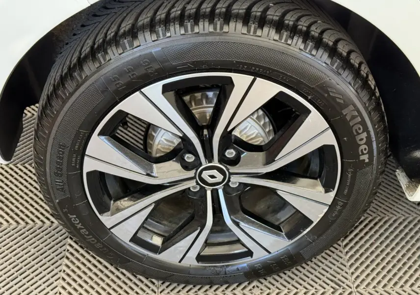 Gros plan sur la roue avant droite d'une Renault Clio blanche 2023 avec jante alliage noire et argent.