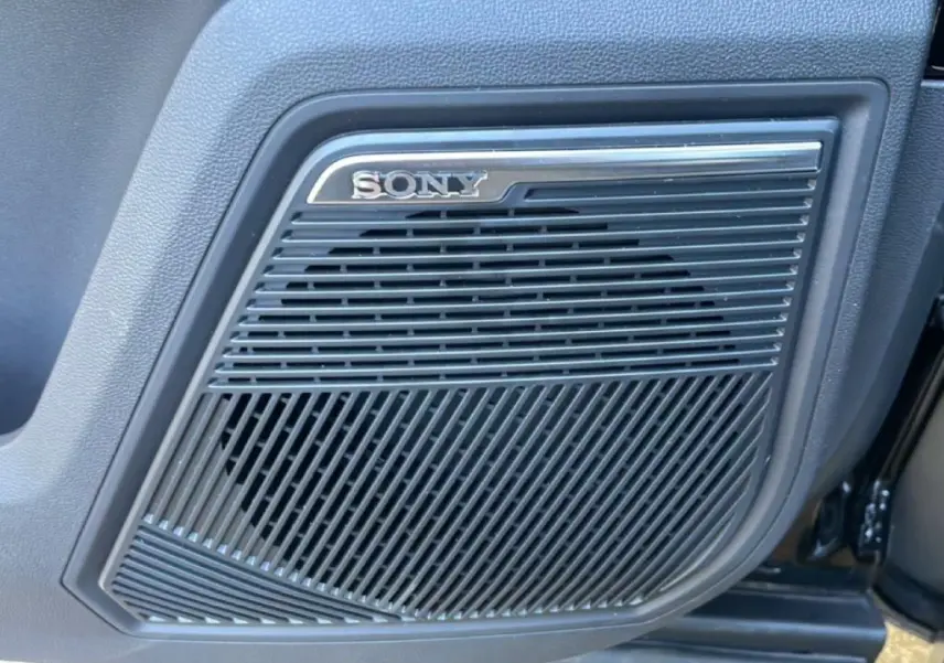 Gros plan sur le haut-parleur Sony intégré à la porte intérieure du JAECOO J7 noir carbone métal.