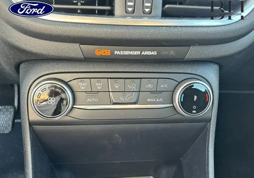 Vue rapprochée du tableau de bord noir de la Ford Fiesta 2023, montrant les commandes de climatisation et l'indicateur d'airbag passager.