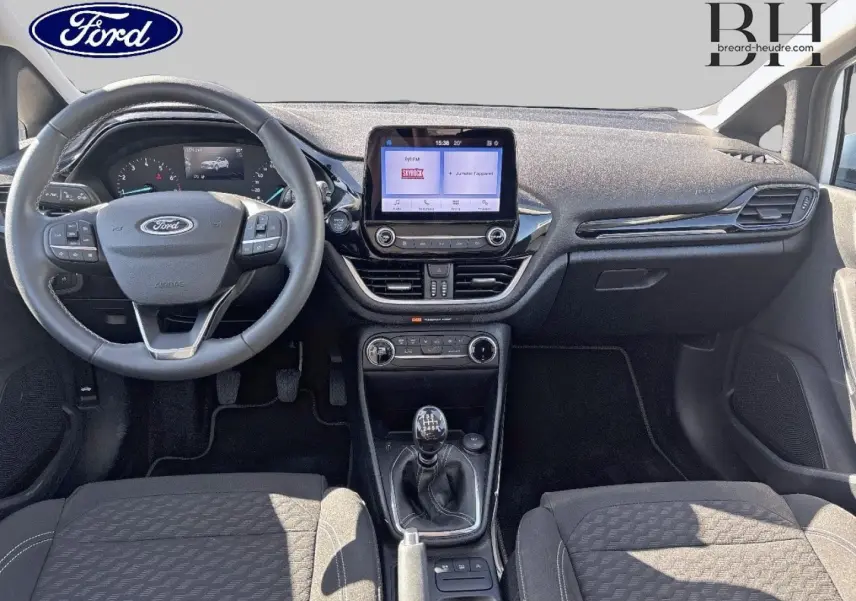 Vue intérieure avant de la Ford Fiesta 2023, montrant le volant cuir, la console centrale avec écran tactile et la boîte manuelle.