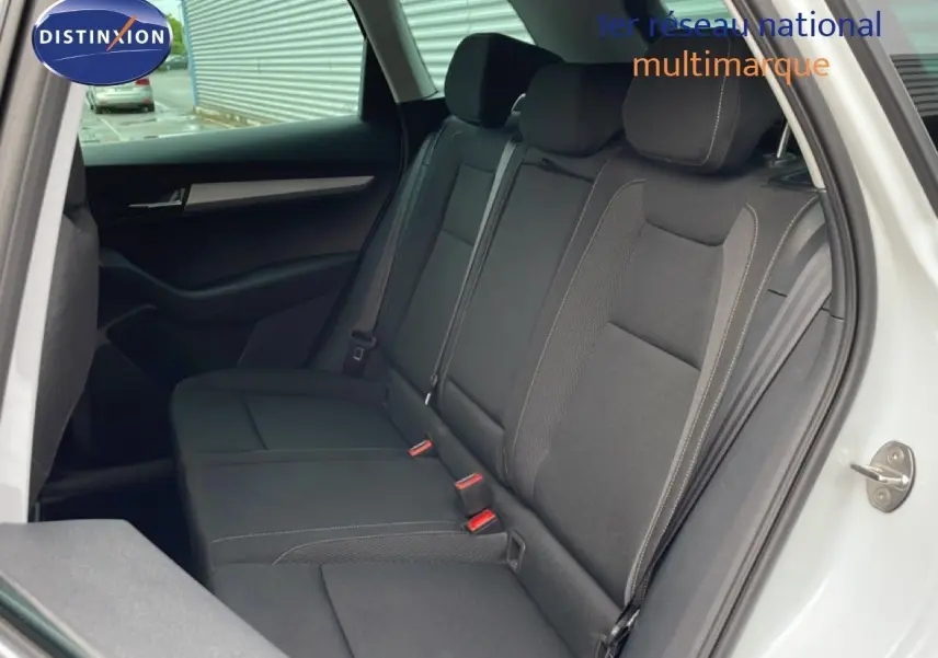 Vue intérieure côté droit des sièges arrière noirs en tissu du Skoda Karoq blanc glacier, avec porte ouverte.
