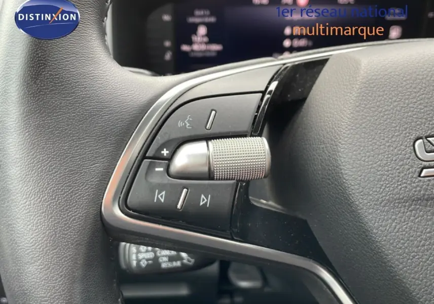 Gros plan sur les commandes gauche du volant cuir noir du Skoda Karoq blanc glacier 2025 avec boutons multifonctions.