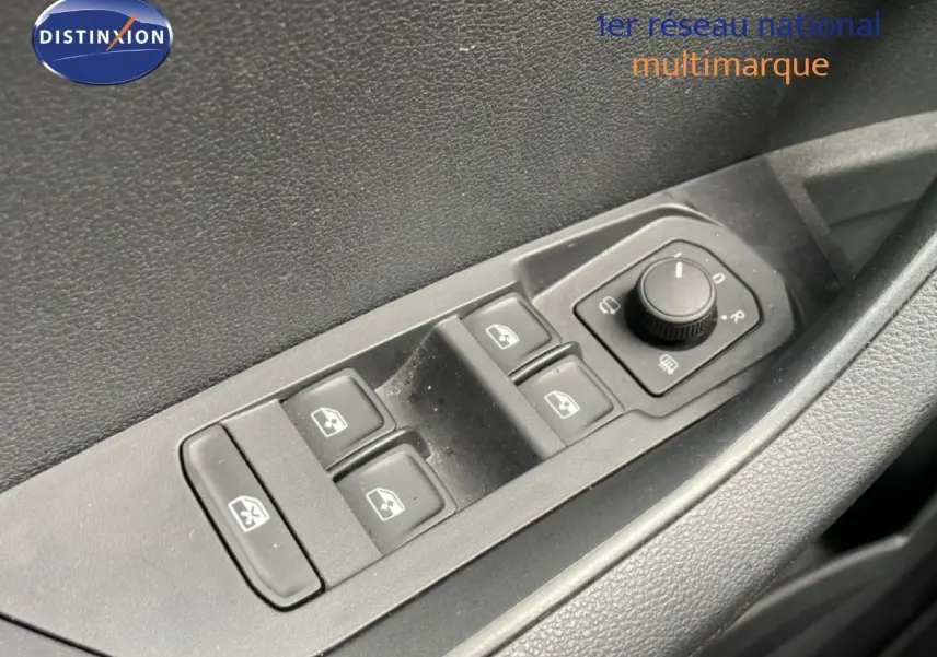Gros plan sur les commandes des vitres et rétroviseurs électriques côté conducteur d’un Skoda Karoq blanc glacier.