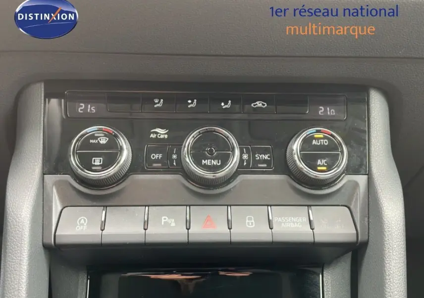 Vue rapprochée sur la console centrale noire du Skoda Karoq blanc glacier, avec commandes climatisation et boutons fonctionnels.