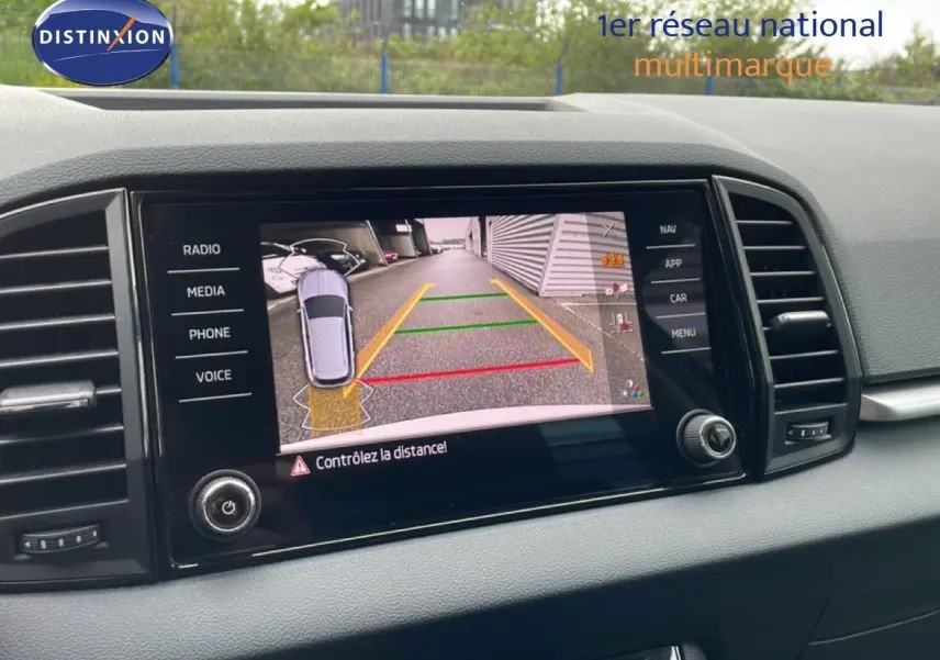 Écran tactile intérieur montrant la caméra de recul du Skoda Karoq blanc glacier, tableau de bord noir.