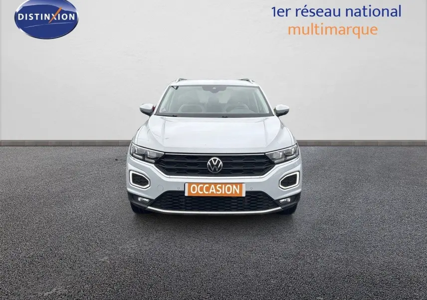 Volkswagen T-Roc blanc argenté vu de face, avec calandre noire et feux LED distinctifs allumés.