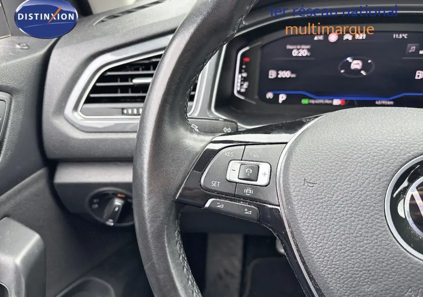 Gros plan sur le volant et le tableau de bord numérique du Volkswagen T-Roc 1.5 TSI blanc argenté, intérieur moderne.