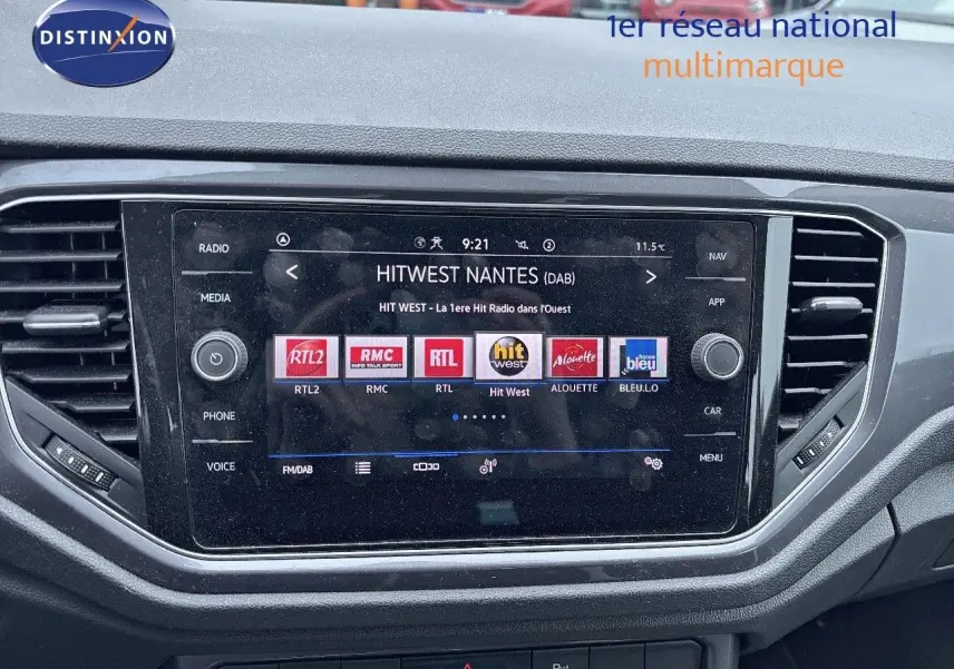 Tableau de bord du Volkswagen T-Roc blanc argenté, avec écran tactile affichant des stations radio numériques.