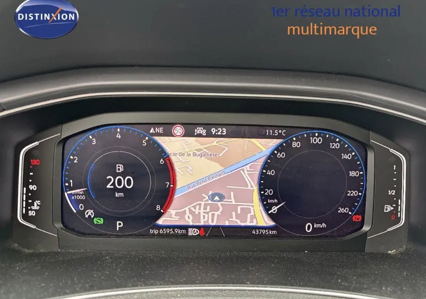 Tableau de bord numérique du Volkswagen T-Roc blanc argenté, affichant la navigation et compteurs à 9h23, intérieur moderne.