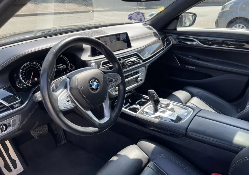 Intérieur noir de BMW Série 7 G11 730 XDA M Sport 2015, vue côté conducteur sur tableau de bord et console centrale moderne.