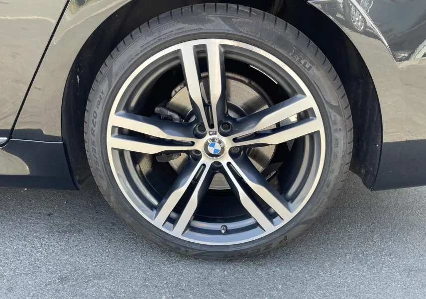 Gros plan sur la roue avant droite noire d'une BMW Série 7 G11 M Sport avec jante alliage cinq branches.