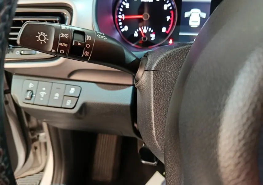 Gros plan sur le commodo d’éclairage et le tableau de bord numérique de la KIA Stonic gris clair, version 2022.