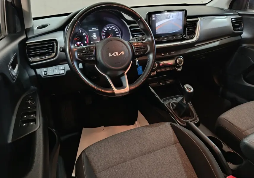 Vue intérieure avant du tableau de bord et volant noir de la KIA Stonic 1.0 T-GDI avec écran tactile et boîte manuelle.