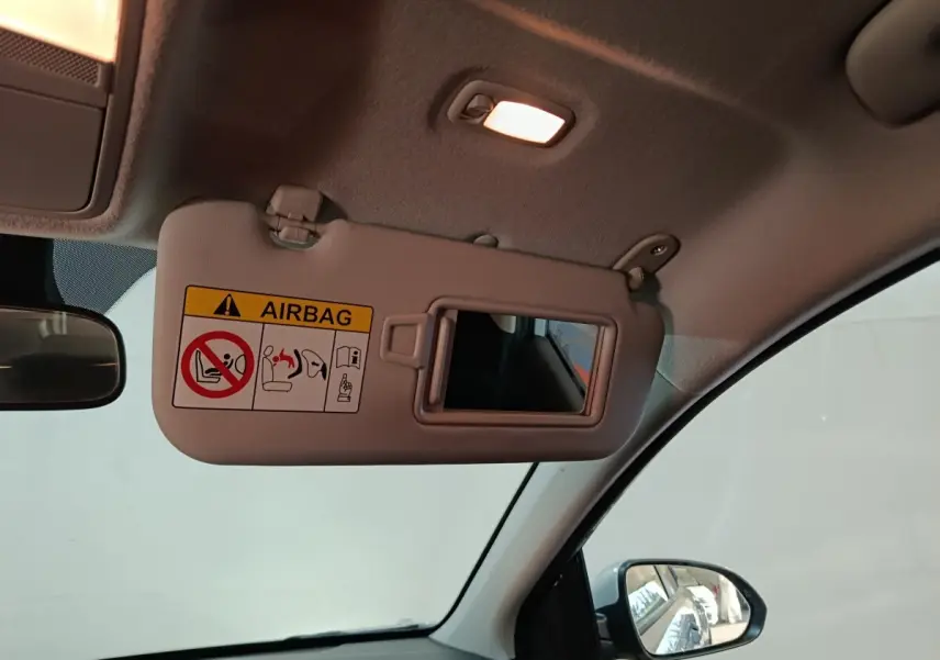 Vue intérieure du pare-soleil côté conducteur avec miroir et avertissement airbag dans un Kia Stonic gris clair 2022.