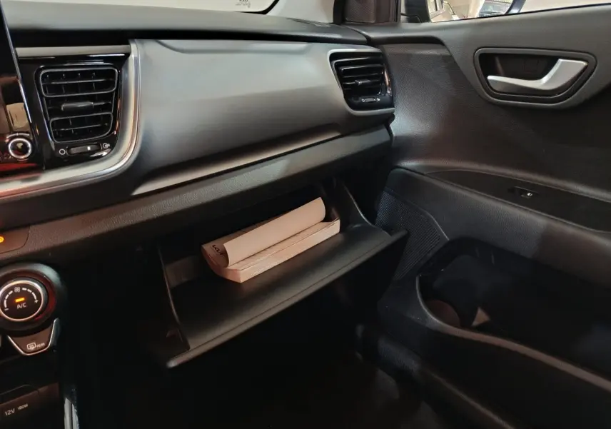 Intérieur côté passager du Kia Stonic gris clair 2022, avec boîte à gants ouverte contenant un manuel.