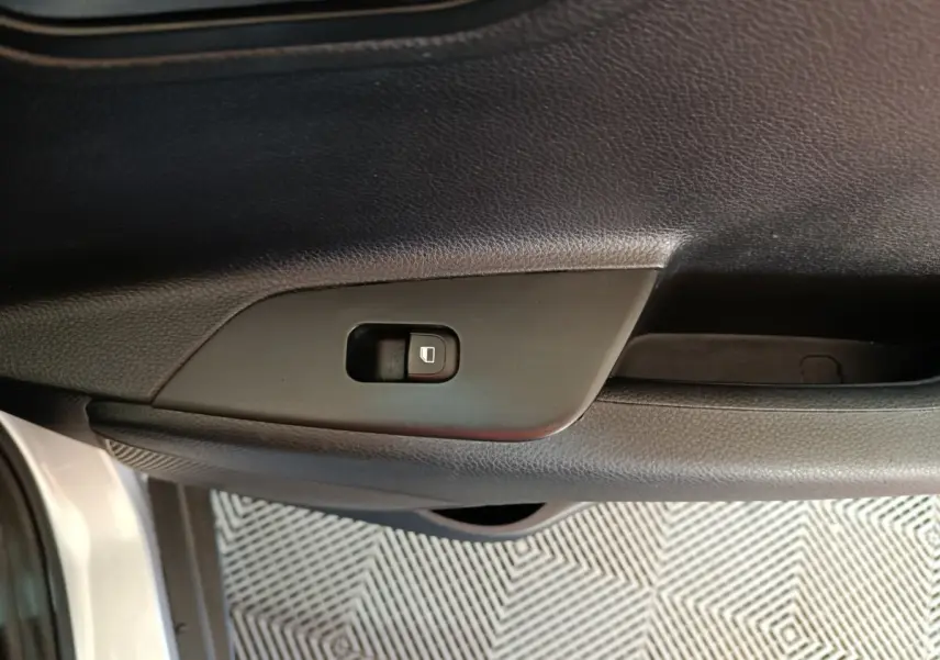 Gros plan sur le bouton de verrouillage de porte côté gauche de la portière intérieure d'une KIA Stonic gris clair 2022.