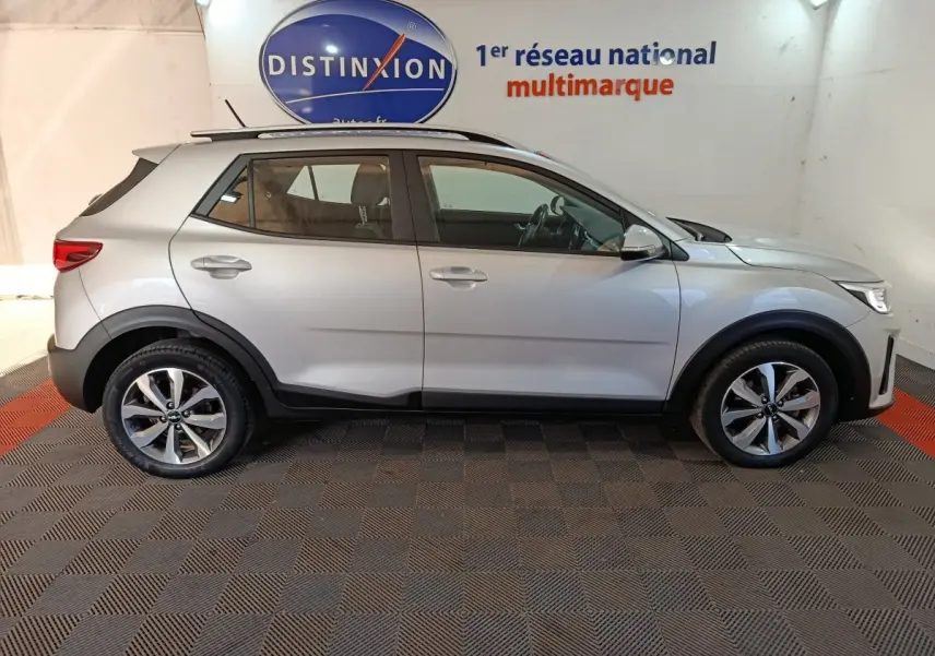 Profil droit d'un KIA STONIC gris clair 2022 en intérieur, avec jantes alliage et détails noirs sur les passages de roues.
