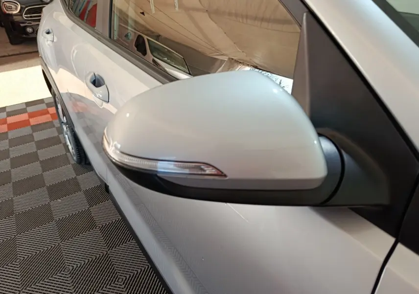 Gros plan sur le rétroviseur côté gauche gris clair du KIA STONIC 1.0 T-GDI 100 URBAN 2022, avec porte et poignée visibles.