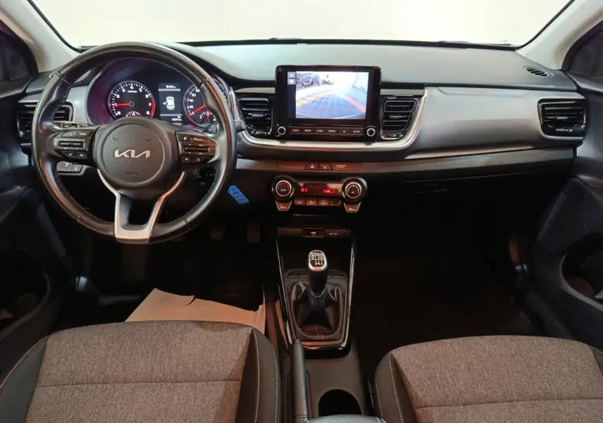 Vue intérieure frontale du tableau de bord gris clair du Kia Stonic 1.0 T-GDI 2022 avec volant multifonction et écran tactile central.