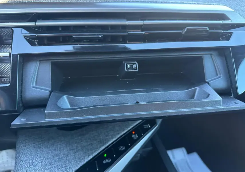 Gros plan sur la boîte à gants ouverte du Peugeot 3008 Hybrid blanc, montrant une prise USB intégrée.