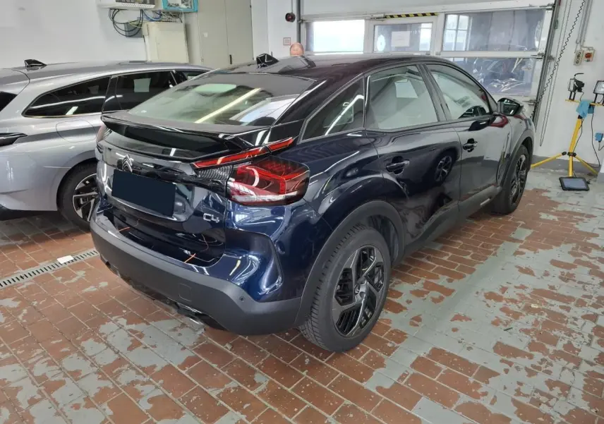 Vue 3/4 arrière droite d'une Citroën C4 2024 Bleu Eclipse avec toit noir et jantes alliage noires.