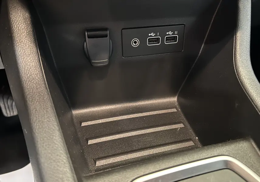 Gros plan sur la console centrale noire de la Renault Clio V, montrant deux ports USB et une prise jack.