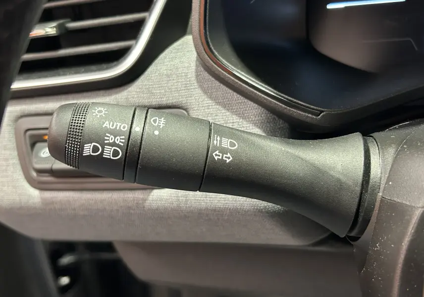 Gros plan sur la manette de commande des phares et clignotants dans l’habitacle gris d’une Renault Clio V TCe 90ch.