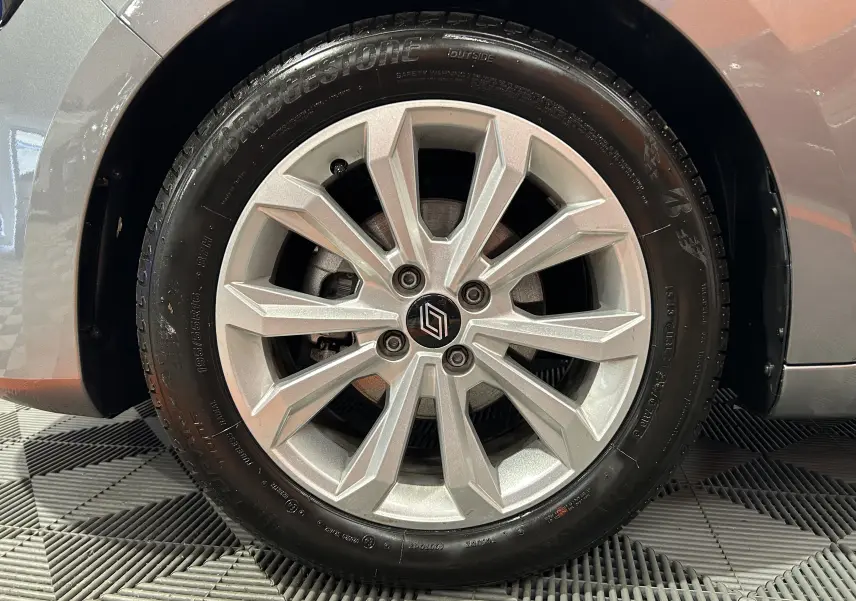 Gros plan sur la roue avant droite d'une Renault Clio V gris schiste métal avec jante alliage à dix branches.