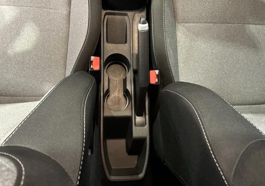 Vue plongeante sur la console centrale noire avec frein à main et sièges tissu gris et noir de la Renault Clio V.