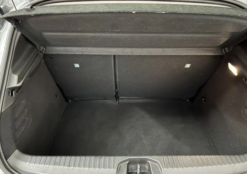 Coffre ouvert en vue plongeante d'une Renault Clio V gris schiste, montrant un espace de chargement propre et vide.