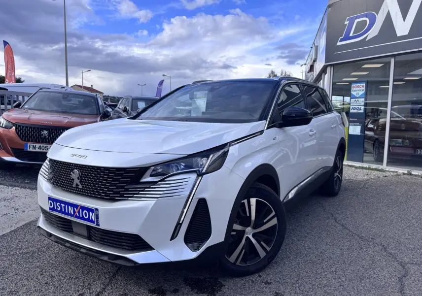 Peugeot 5008 blanc en 3/4 avant droit, avec calandre noire distinctive et jantes alliage bicolores.