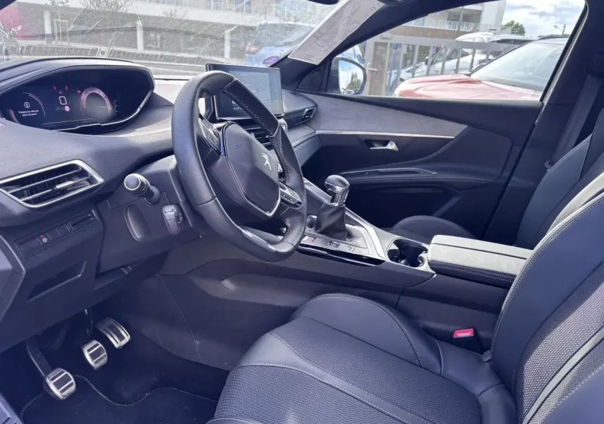Intérieur du Peugeot 5008 2022 blanc, vue côté conducteur, volant compact, boîte manuelle et sièges en cuir noir.