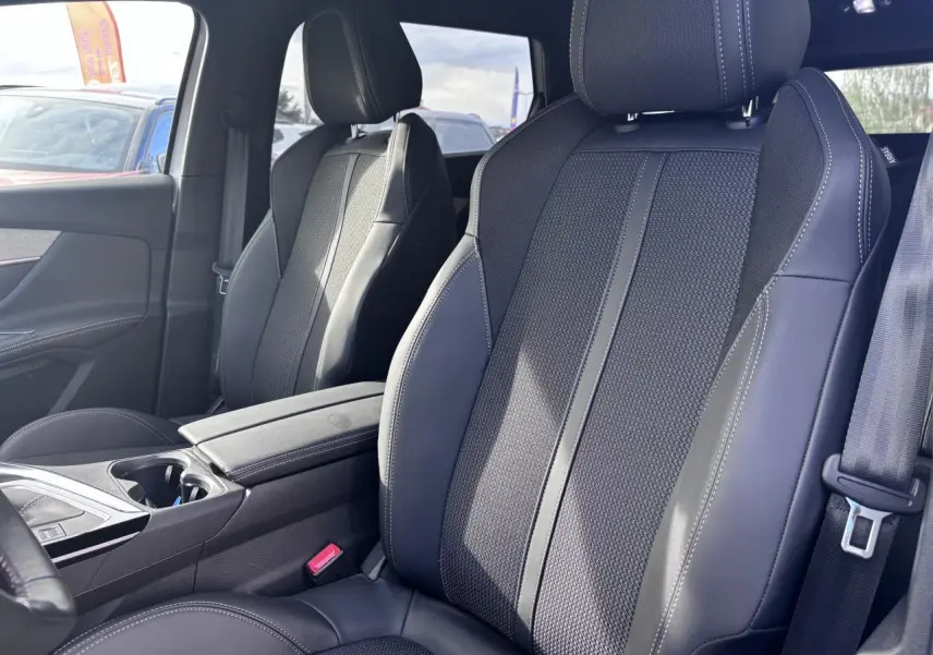 Vue intérieure rapprochée des sièges avant en tissu et cuir noir du Peugeot 5008 GT 2022, avec accoudoir central.