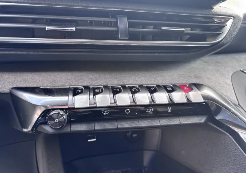 Détail de la console centrale avec les boutons métalliques et la grille d'aération du Peugeot 5008 blanc, version GT 2022.