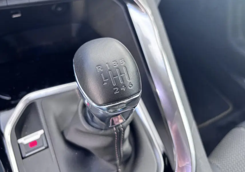 Le levier de vitesse manuel noir du Peugeot 5008 blanc, avec indication des six rapports et de la marche arrière.