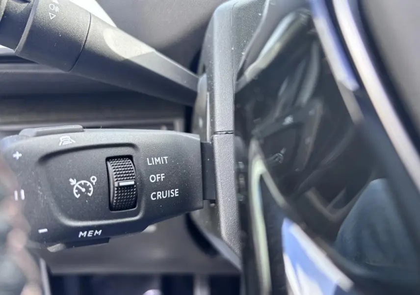 Gros plan sur la commande de régulateur de vitesse du Peugeot 5008 blanc, vue côté gauche du volant.