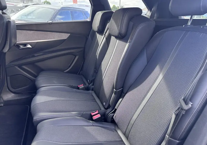 Vue latérale droite sur les sièges arrière noirs en tissu et cuir du Peugeot 5008 blanc, version GT 2022.