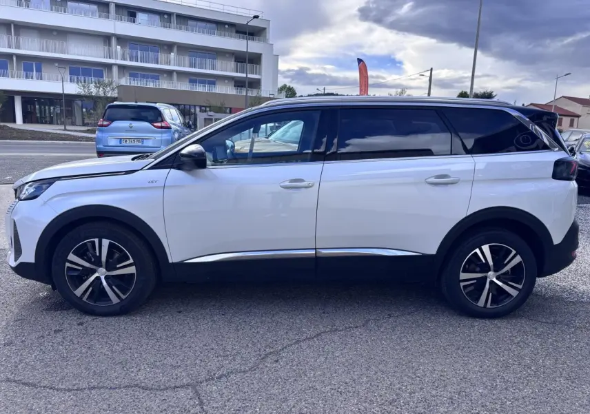 Vue de profil côté gauche d’un Peugeot 5008 blanc 2022 avec jantes alliage et toit noir contrasté.