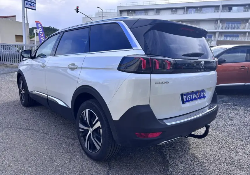 Vue 3/4 arrière droite d'un Peugeot 5008 blanc 2022 avec feux arrière LED et attelage visible.