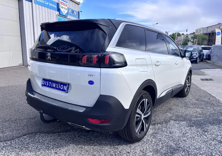 Vue 3/4 arrière droite d'un Peugeot 5008 blanc 2022 avec toit noir et feux arrière à griffes rouges distinctifs.